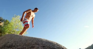 Ağır çekim genç adam göle günbatımında atlama  