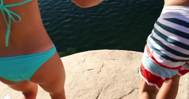 Happy Young Adult Couple Holding Hands Jumping Lake — Stock Video