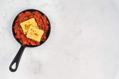 Soğanlı, biberli ve baharatlı domates soslu tofu. Geleneksel Arap ve İsrail kahvaltısının vejetaryen versiyonu. Chakchouka, ekşi ekmek ve gri arka planla servis edilir. Sağlıklı, sıcak bir kahvaltı. Tekst ışık arkaplanına yerleştir.