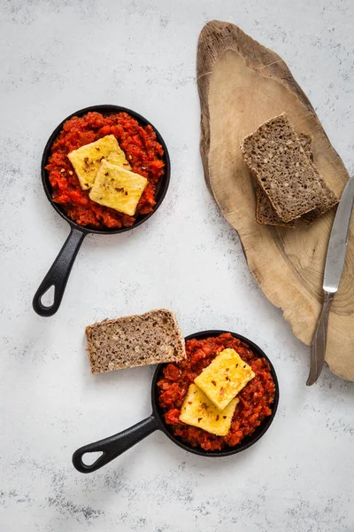 Soğanlı, biberli ve baharatlı domates soslu tofu. Geleneksel Arap ve İsrail kahvaltısının vejetaryen versiyonu. Chakchouka, ekşi ekmek ve gri arka planla servis edilir. Sağlıklı, sıcak bir kahvaltı. Hafif arkaplan.