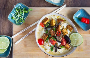 Sebzeli Tayland baharatlı çorba, tofu, hindistan cevizi sütü, limon yaprağı, kırmızı biber ve galangal kökü tozu. Vejetaryen, sağlıklı yemek, glütensiz. Ahşap arkaplan, üst manzara.