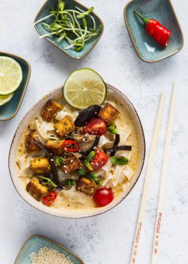 Sebzeli Tayland baharatlı çorba, tofu, hindistan cevizi sütü, limon yaprağı, kırmızı biber ve galangal kökü tozu. Vejetaryen, sağlıklı yemek, glütensiz. Beyaz arkaplan, üst görünüm.