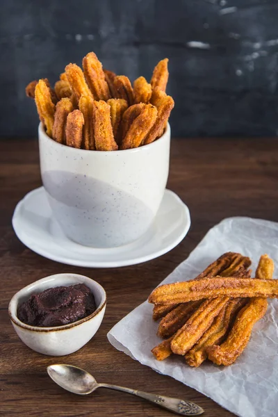 Tarçın şekeri ve çikolata soslu ev yapımı vejetaryen churro. Koyu arkaplan.