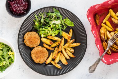 Fırında patates, pancar kökü ve marulla servis edilen yeşil mercimekli vegan burger (pirzola). Sağlıklı vejetaryen diyeti. Beyaz arkaplan, üst görünüm.