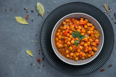 Kırmızı ve yeşil dolmalık biberli nohut yahnisi, gri arka plan, üst manzara. Sağlıklı vejetaryen gıda konsepti. Yüksek proteinli yemek, kırmızı biber. Tekst için yer.