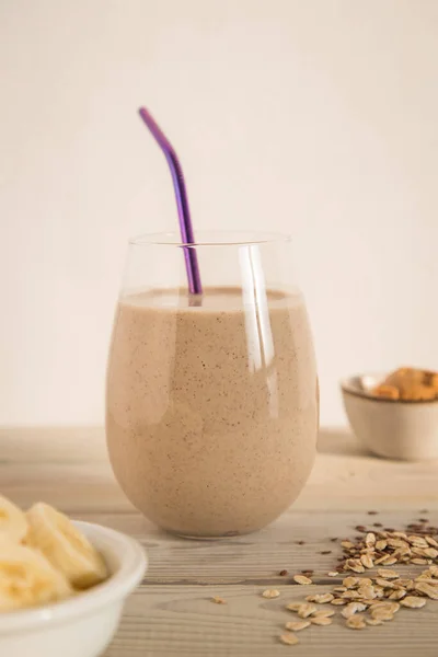 Fıstık ezmeli muzlu smoothie ve arka planda bir bardakta yulaf ezmesi. Kahvaltı kokteyli. Sağlıklı beslenme.