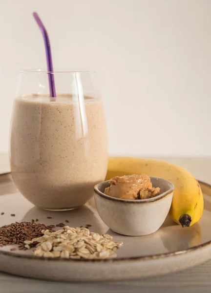 Fıstık ezmeli muzlu smoothie ve arka planda bir bardakta yulaf ezmesi. Kahvaltı kokteyli. Sağlıklı beslenme.