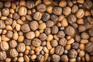 Tahta bir tabakta kabuklu fındıklar. Ceviz, badem, fındık ve Brezilya fındığı çeşitleri. Sağlıklı beslenme kavramı.