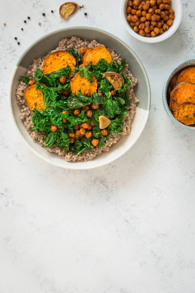 Vegan dish with buckwheat, chickpeas, sweet potato, and kale in a bowl. Comfort food.