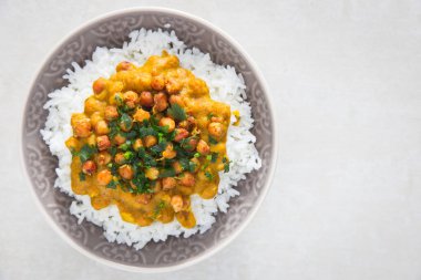 Hint vejetaryen chana masala. Baharatlı nohut körisi, maydanozlu domates sosu, tabakta pilav ile servis edilir..