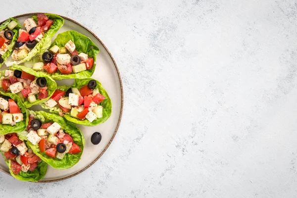 Fit snack made of tomato, tofu, cucumber and olives served in a romaine lettuce leaf. Fitness food. Lunch. Nutrition concept.