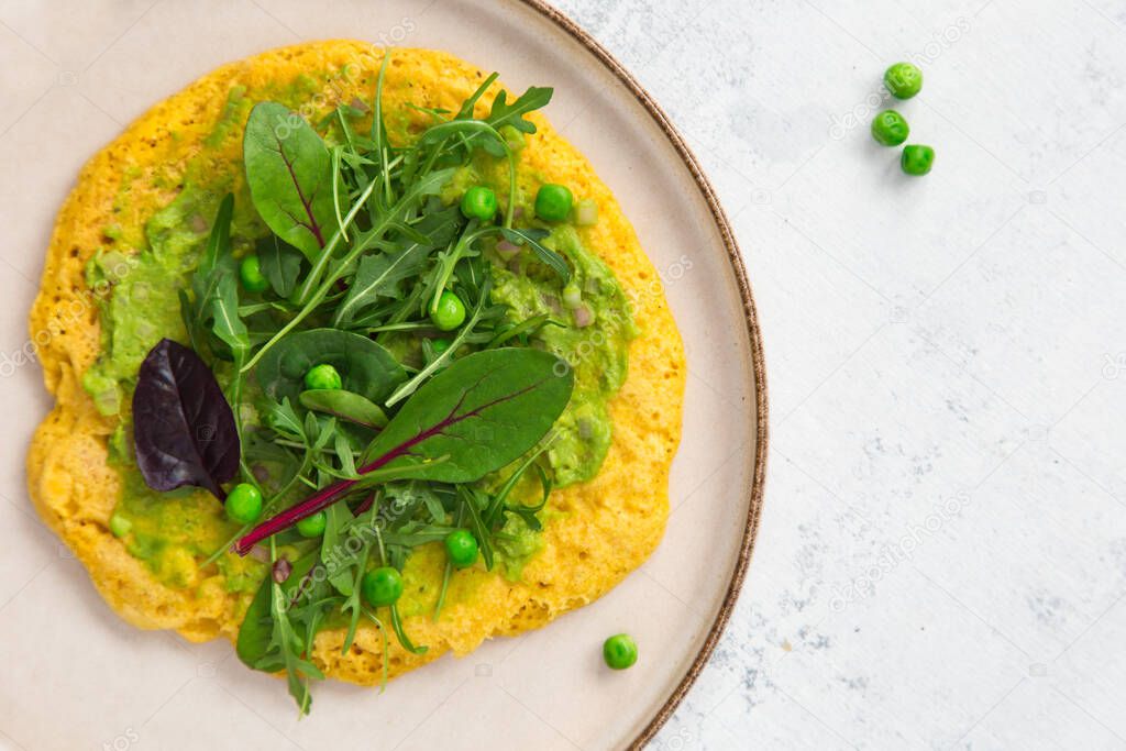 Vegan chickpea omelet with tofu, guacamole and greens on a  plate. Healthy vegan food concept.