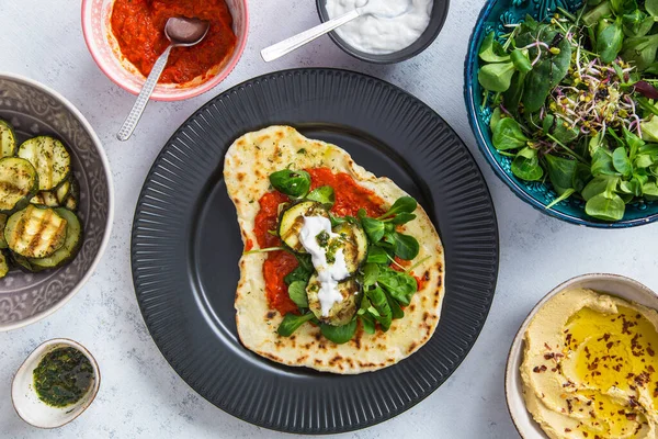 Tabakta baharatlı sarımsaklı Hint ekmeği. Humus, ayvar, ızgara kabak, yoğurt ve yeşil marul ile servis edilir..