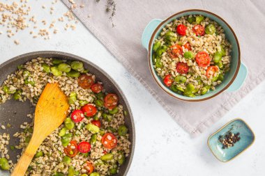 A healthy snack, lunch or dinner. Bowl and pan of pearl barley with broad beans and cherry tomatoes. A healthy snack, lunch or dinner. Vegan comfort food. View from the top. clipart