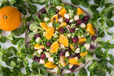 Kuzu marulundan yapılmış renkli bir salata, kavrulmuş pancar kökü, vegan peyniri ve portakal. Sağlıklı vejetaryen yemekleri.