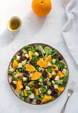 Kuzu marulundan yapılmış renkli bir salata, kavrulmuş pancar kökü, vegan peyniri ve portakal. Sağlıklı vejetaryen yemekleri.