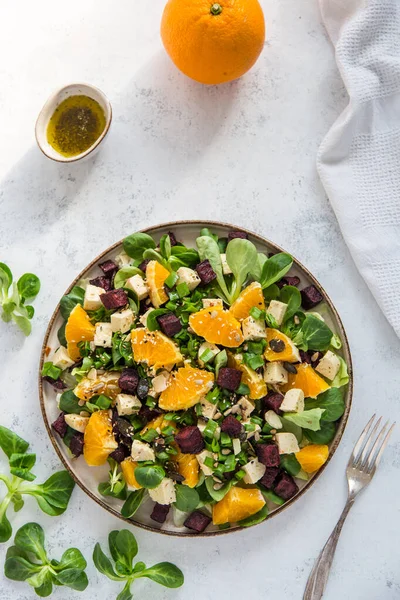 Kuzu marulundan yapılmış renkli bir salata, kavrulmuş pancar kökü, vegan peyniri ve portakal. Sağlıklı vejetaryen yemekleri.