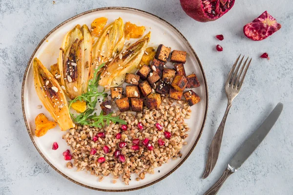 Delicious and healthy vegan dinner or lunch  low in calories and high in protein. Buckwheat groats with grains and pomegranate, chicory with orange and fried tofu.