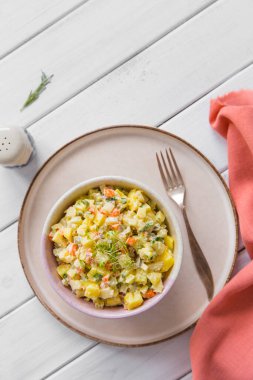 Kaynamış kök sebzeli salata, salatalık turşusu, elma, mayonez ve hafif ahşap arka planda bir kasede. Parlak bir arka planda geleneksel Polonya salatası. Üst görünüm, düz görünüm.