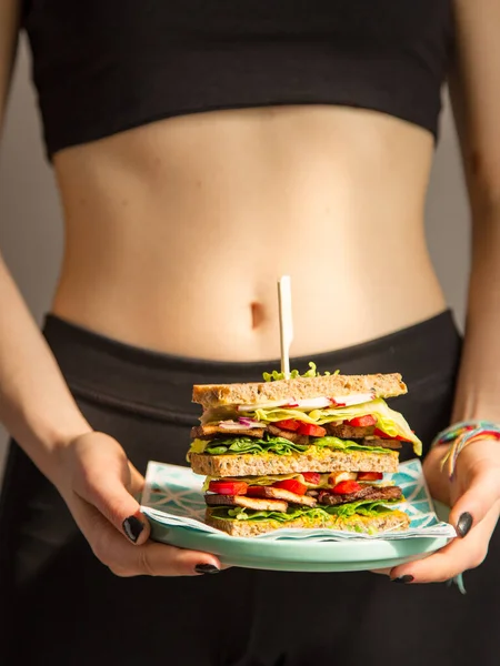 一个身材苗条的小女孩手拿着一个健康的三明治 在锻炼之后 全麦面包三明治加新鲜生菜和豆腐 健康食品 — 图库照片