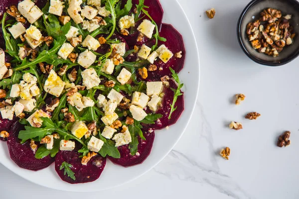 Vejetaryen pancar carpaccio salatası roka, tofu peyniri, zeytin sirkesi ve seramik tabakta ceviz. Üst manzara, boşluk. Sağlıklı beslenme.