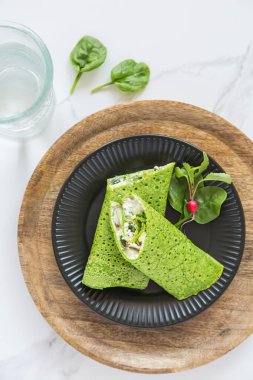 Yeşil bahar vejetaryen ıspanaklı krep ya da kremalı vejetaryen peynirli krep ve erken sebze. Sağlıklı vejetaryen yemekleri, ev yapımı kahvaltı, manzaralı.