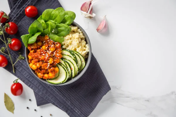 A healthy vegan dinner bowl. Chickpeas in tomato sauce, zucchini salad, porridge and spinach on a light background.