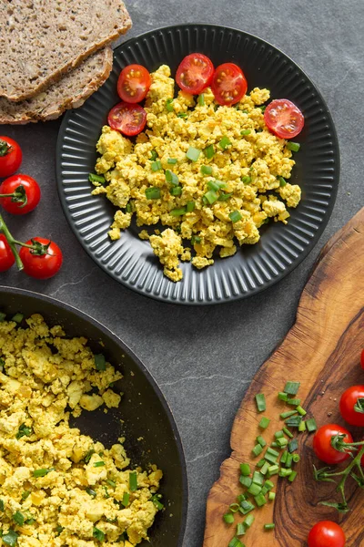 Tofu scramble with tomatoes and greens on toast on a  plate. Healthy vegan food concept.