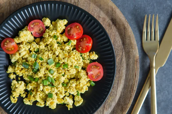 Tofu scramble with tomatoes and greens on toast on a  plate. Healthy vegan food concept.