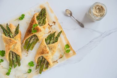 Parmesanlı vejetaryen peynirli puf böreğinde pişirilmiş yeşil kuşkonmaz. Tekst için yer.