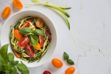 Çiğ vejetaryen kabaklı julienne şehriye fesleğen pesto ve vişneli domatesle servis edilir. Vejetaryen sağlıklı yemek. Tekst için yer.