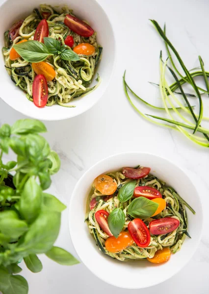 Çiğ vejetaryen kabaklı julienne şehriye fesleğen pesto ve vişneli domatesle servis edilir. Vejetaryen sağlıklı yemek.