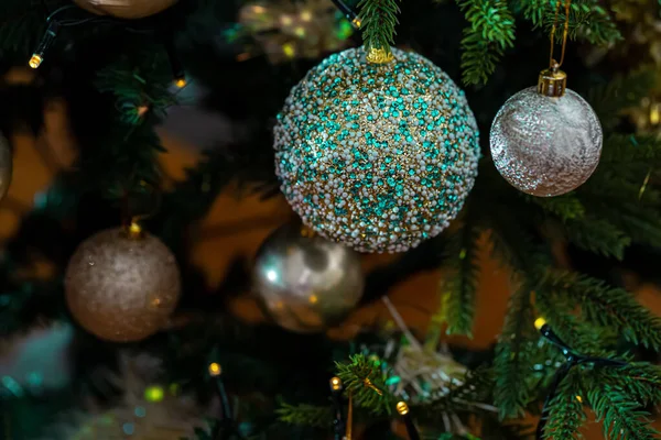 Hermosa bola verde en una rama de pino o árbol de Navidad. Fondo oscuro y guirnalda con luz amarilla. Enfoque suave —  Fotos de Stock