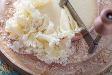 Yuvarlak İsviçre peyniri Monk 'un kafası ahşap bir tahta ve özel metal bir bıçak üzerinde. Yumuşak odaklanma. Yakın plan.