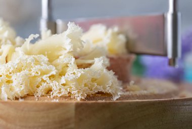 Cheese on a wooden round board and a special metal knife. Soft focus. 