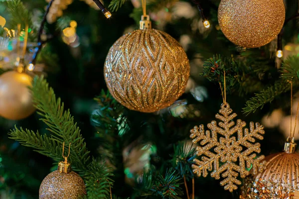 Décorations festives en or boules et flocons de neige sur le sapin de Noël et beau bokeh jaune de guirlande éclatante. Fond sombre Images De Stock Libres De Droits