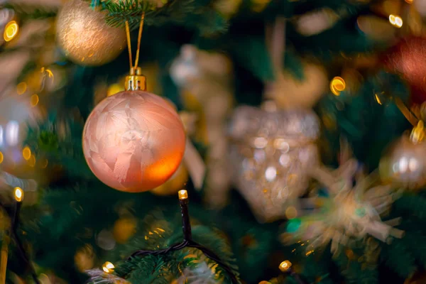 Pinkfarbener Festschmuck am Weihnachtsbaum und ein wunderschönes gelbes Bokeh aus leuchtenden Girlanden. Kopierraum. — Stockfoto