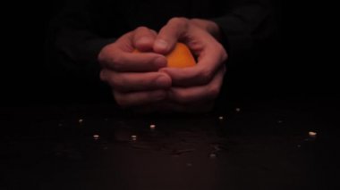 Erkekler koyu arkaplanda sarı bir portakalın iki parçasını tutmayı teklif eder.