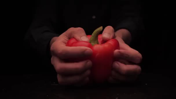 男性の手は暗い背景に赤ピーマンの2枚を保持するために提供 — ストック動画