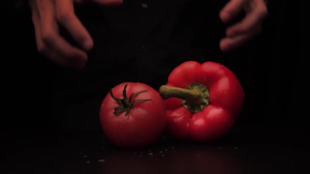 Um homem mãos pegar uma pimenta vermelha e tomate em um fundo escuro da mesa — Vídeo de Stock