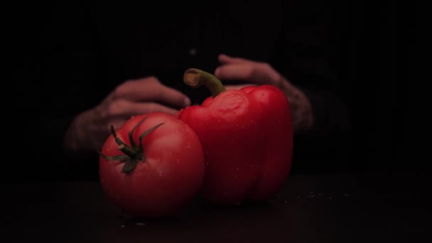Um homem mãos pegar uma pimenta vermelha e tomate em um fundo escuro da mesa — Vídeo de Stock