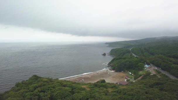 Aerial view of glass beach, Russky Island, Vladivostok. Water, forest, coast and fog, road in the forest. A bird flies — Stock Video