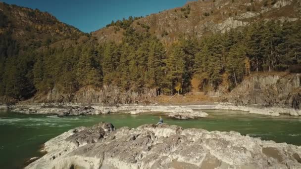 Luftaufnahme des Gebirgsflusses Katun. Junges Mädchen, das auf Felsen geht. Ein wunderschönes herbstliches Gebirgstal mit Wald. Chemal Dorf, Republik Altai, Russland — Stockvideo