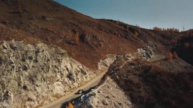 Yüksek irtifada Serpentine dağ yolunun havadan görüntüsü. Güzel sonbahar altın vahşi manzarası: dolambaçlı zorlu yol, orman, sarı ve kırmızı yapraklı ağaçlar, büyük dağlar, sarp kayalıklar