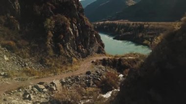 Sakin dağ nehri Katun 'un havadan görünüşü. Altai Bölgesi 'nin vahşi sonbahar manzarası: dağlar, ormanlar, tarlalar, bir ülke yürüyüş yolu, bir dağ deresi, güneş ışınları.