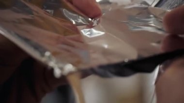 Bir kızın uzun kahverengi saçlarını ön plana çıkarma sürecine yakın plan. Kuaför, kızın güçlü ve güzel saçlarını boyamak, saçlarını taramak, ıslak saçlarını folyoya sarmak için hazırlar.