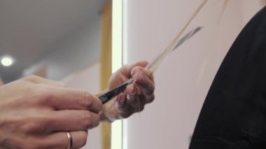 Saç sağlığı için bir kızın uzun kahverengi saçlarını ön plana çıkarma ve kesme sürecine yakın plan. Kuaför, kızın güçlü ve güzel saçlarını taramak, kesmek ve taramak için hazırlar.