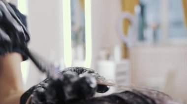 Saç sağlığı için uzun kahverengi saçlı kızları ön plana çıkarma ve yıkama sürecine yakın çekim. Eldivenli kuaför, kızın güçlü güzel saçlarını renklendirme, yıkama ve...