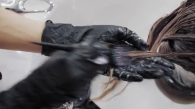 Saç sağlığı için uzun kahverengi saçlı kızları ön plana çıkarma ve yıkama sürecine yakın çekim. Eldivenli kuaför, kızın güçlü güzel saçlarını renklendirme, yıkama ve...