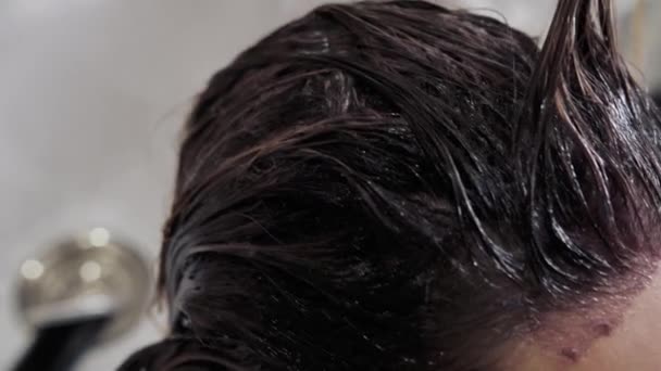 Detailní záběr procesu zvýrazňování a mytí dívek dlouhé hnědé vlasy pro zdraví vlasů. Kadeřník v rukavicích připravuje silné krásné vlasy dívky pro zvýraznění, mytí a — Stock video